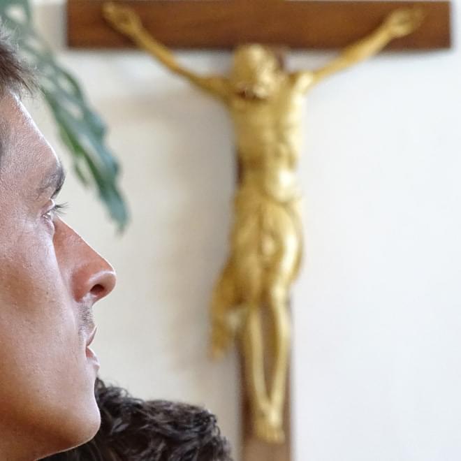 A young man praying in front of the Crucifix